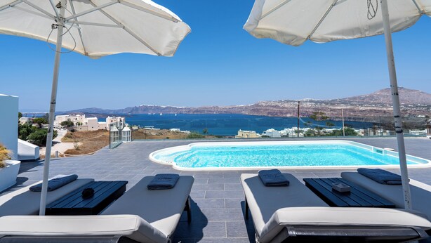 A poolside area with two sun loungers and white umbrellas, overlooking a clear blue sea and distant hills. - The Zen Villa (Santorini)