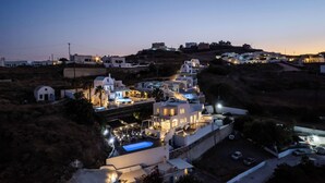 A coastal village with white buildings, a swimming pool, and a hilly backdrop. - The Zen Villa (Santorini)