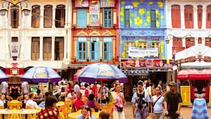A bustling street scene with people dining at outdoor tables, colorful buildings, and various shops. - CUBE Family Boutique Capsule Hotel (Singapore)