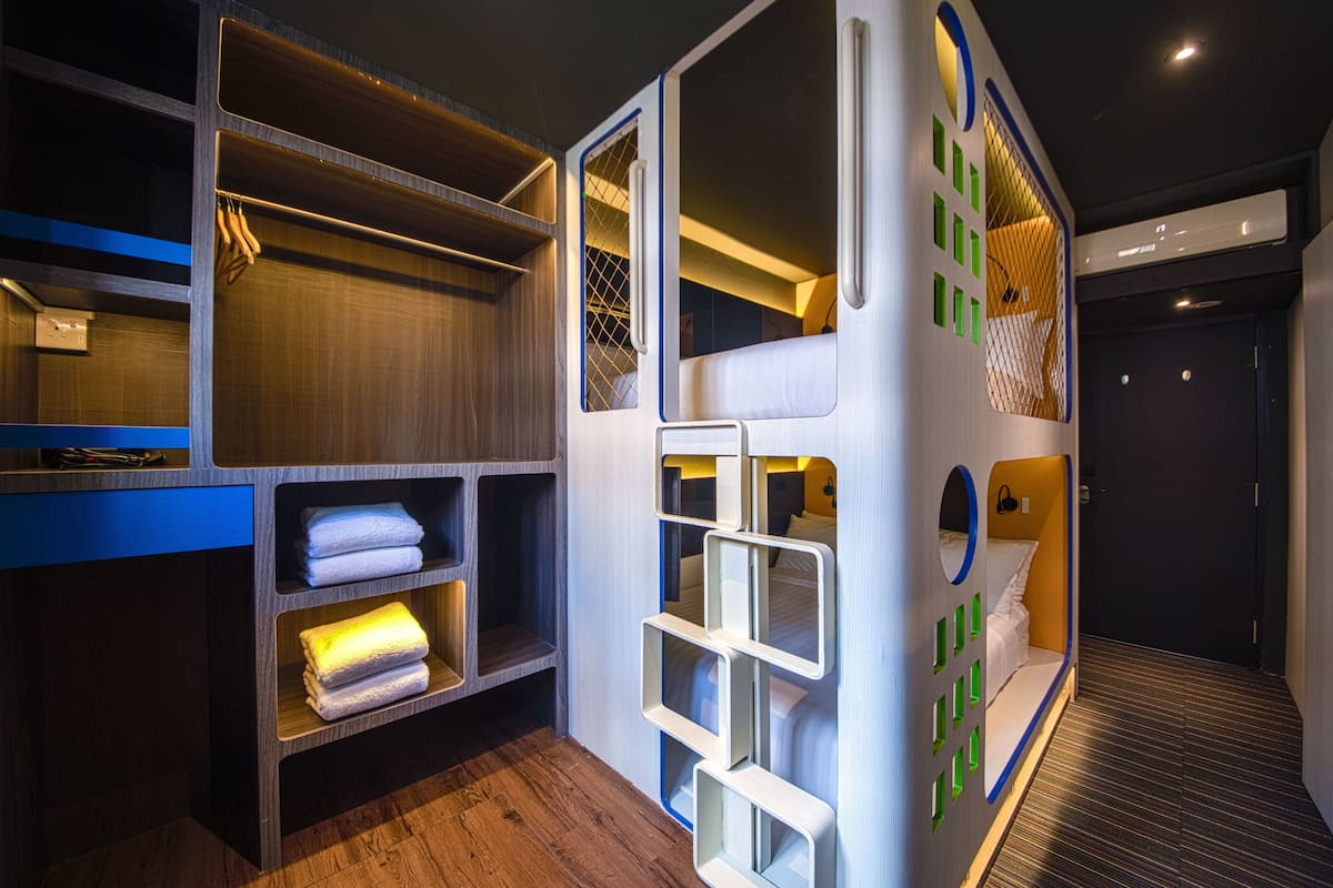 Ein Spielbereich für Kinder mit einem Etagenbett, Stauraumschränken und einem kleinen Rundfenster.