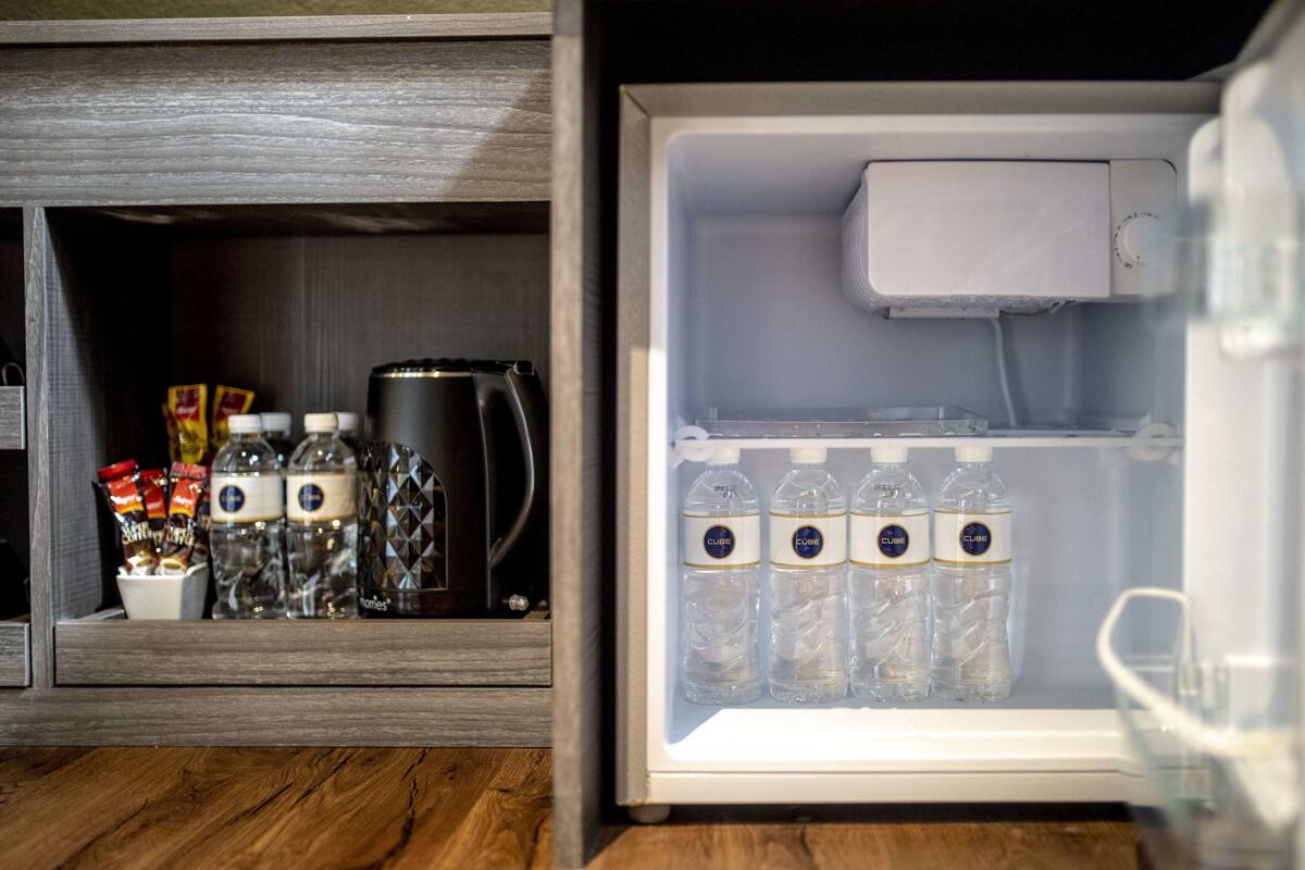 Ein Kühlschrank mit Kaffeemaschine, Wasserflaschen und Gewürzen.