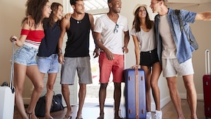 A group of people standing in a room with a suitcase and a red suitcase on the floor. - CUBE Family Boutique Capsule Hotel (Singapore)
