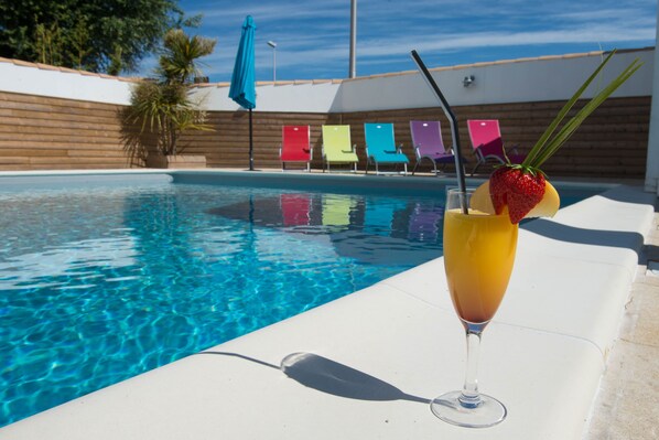 Una piscina al aire libre, sillones reclinables de piscina