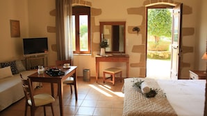 A bedroom with a bed, a desk, a TV, and a view of the outdoors. - Secreto Studios (Kissamos)