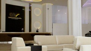 Ein moderner Empfangsbereich mit einer Rezeption, einer Sitzecke mit weißen Sofas und einer großen Säule.
