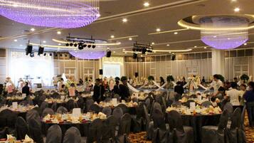 A banquet hall with round tables, gray chairs, and purple chandeliers.