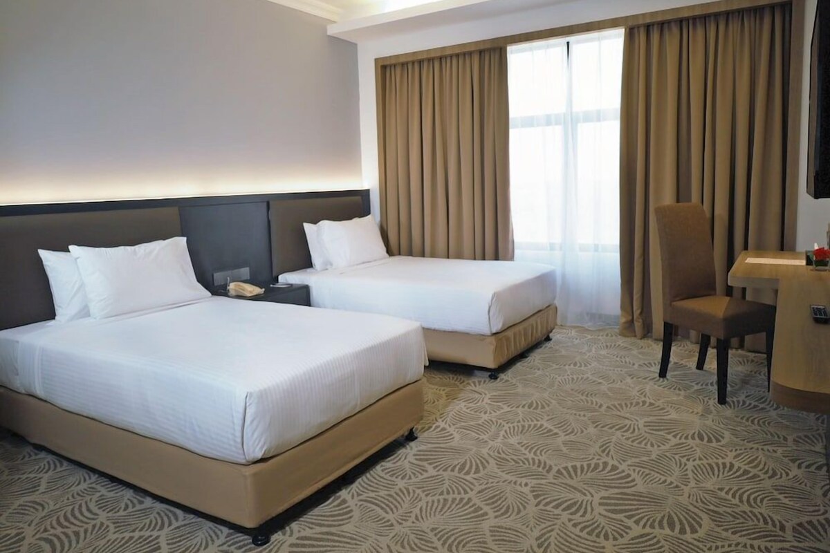Een hotelkamer met twee bedden, een bureau en een stoel.