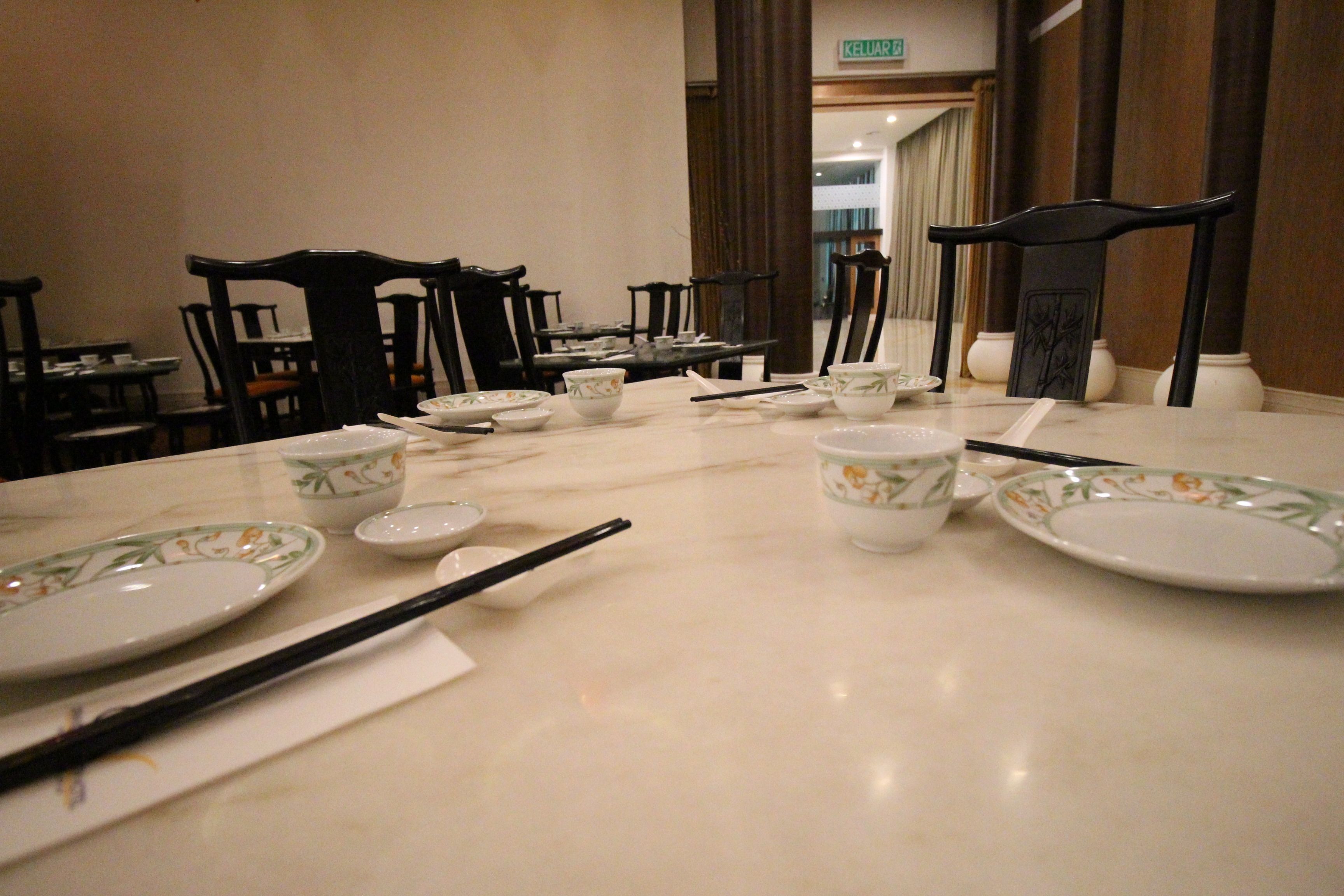Un comedor con una mesa de mármol, sillas negras y diferentes platos y cubiertos.