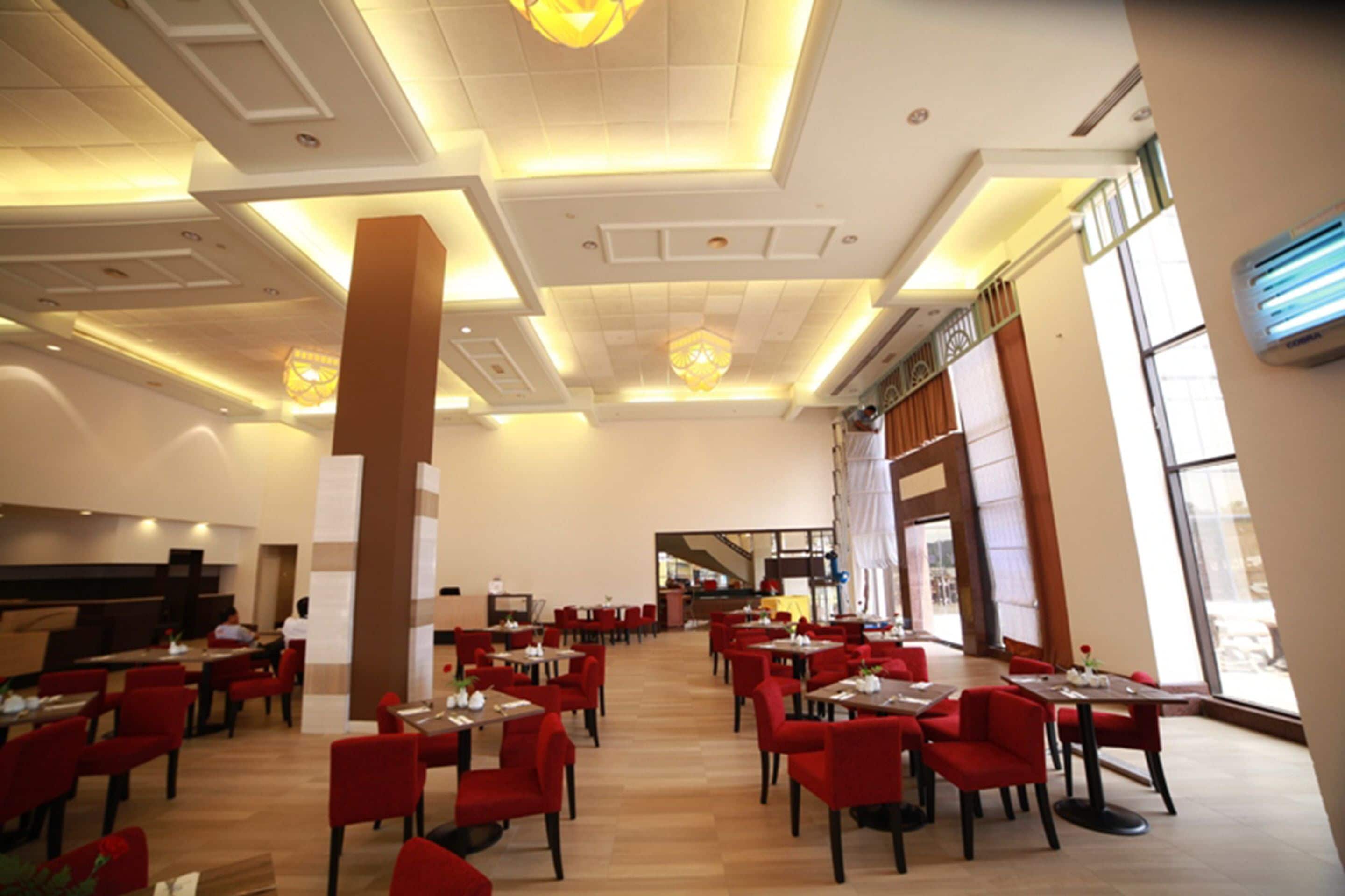 A spacious restaurant with high ceilings, modern lighting, and large windows.