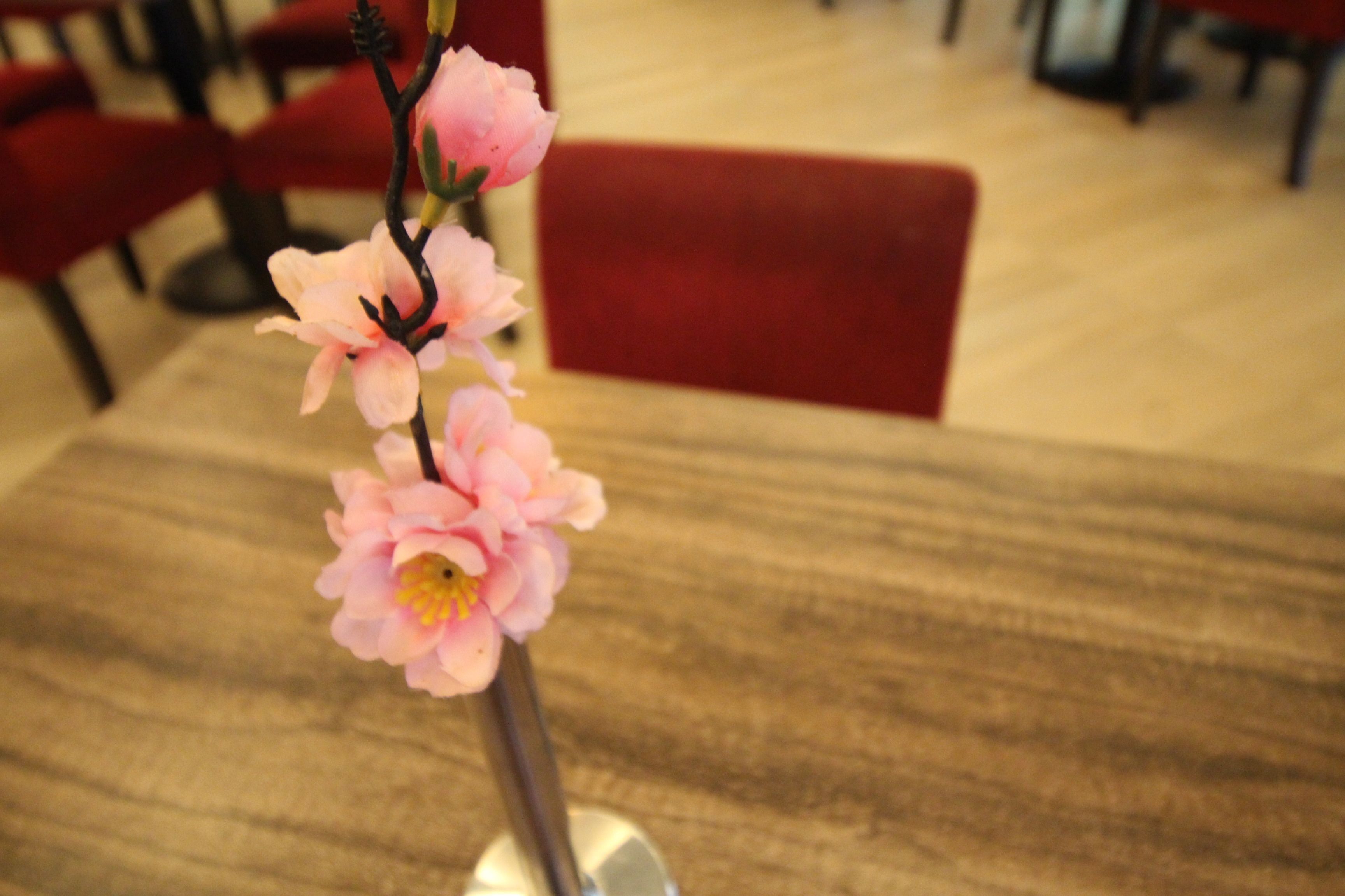 A table with a vase containing pink flowers.