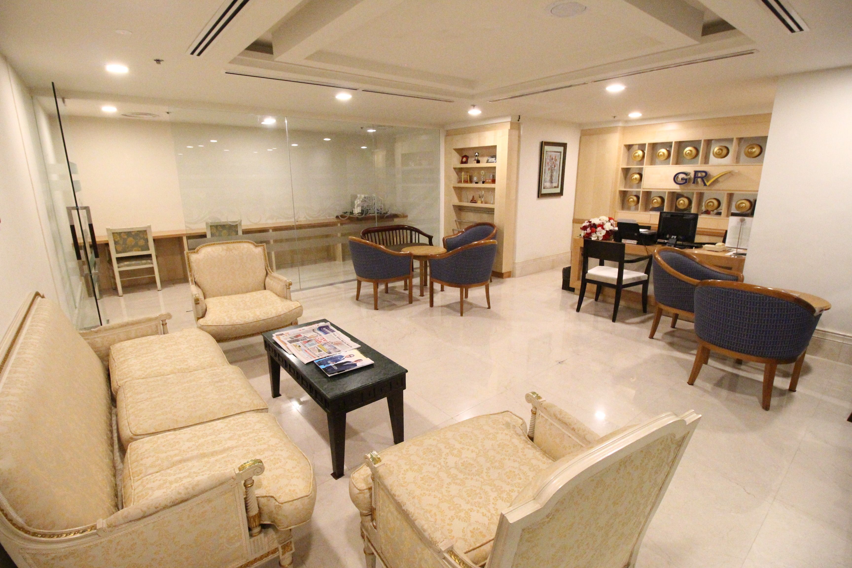 A spacious living area with a sofa set, armchairs, a coffee table, and a dining table with chairs.