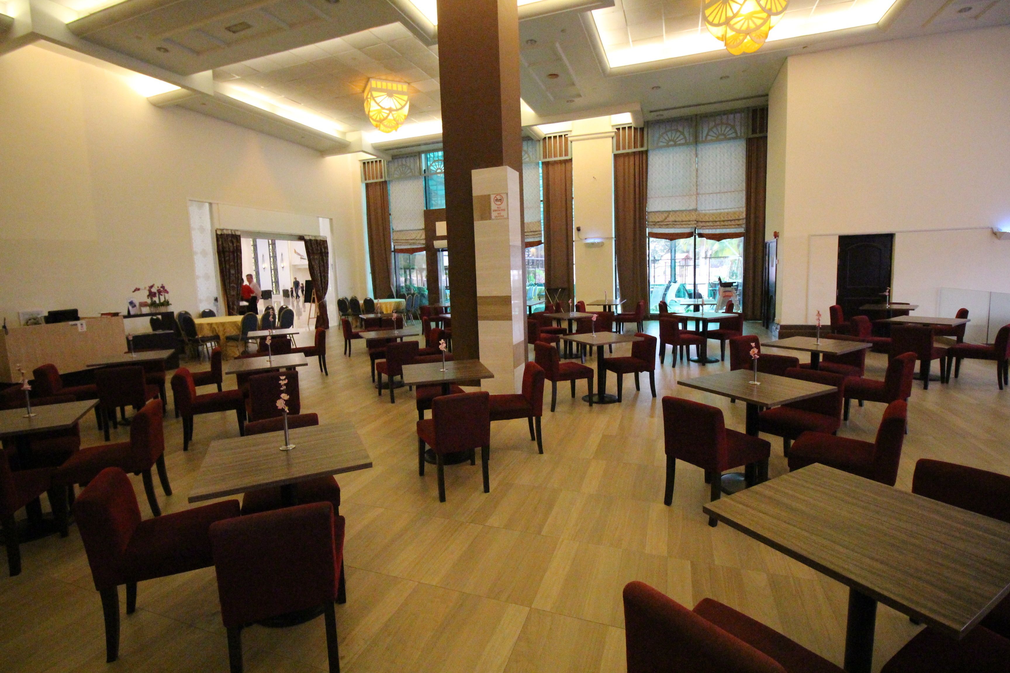 A spacious restaurant with multiple tables and chairs, large windows, and a modern interior design.