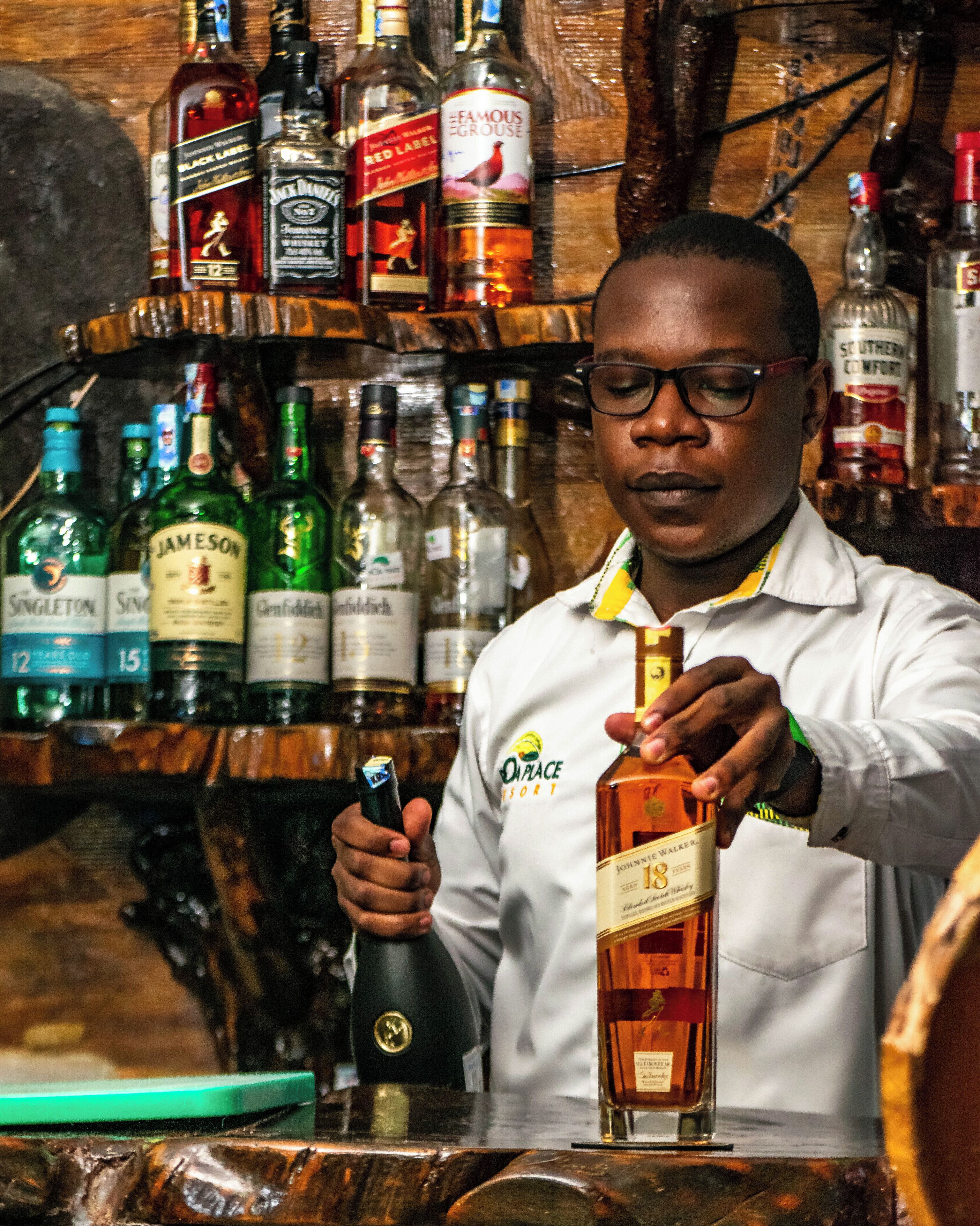 Um bartender servindo uma bebida de uma garrafa para um copo.