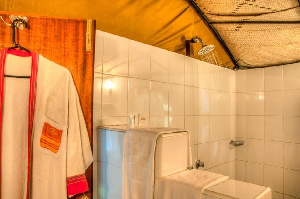 A bathroom with white tiles, a towel rack with a towel, and a shower area.