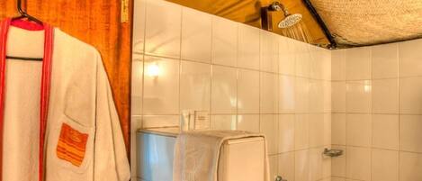 Un baño con azulejos blancos, un perchero con toalla y una zona de ducha.