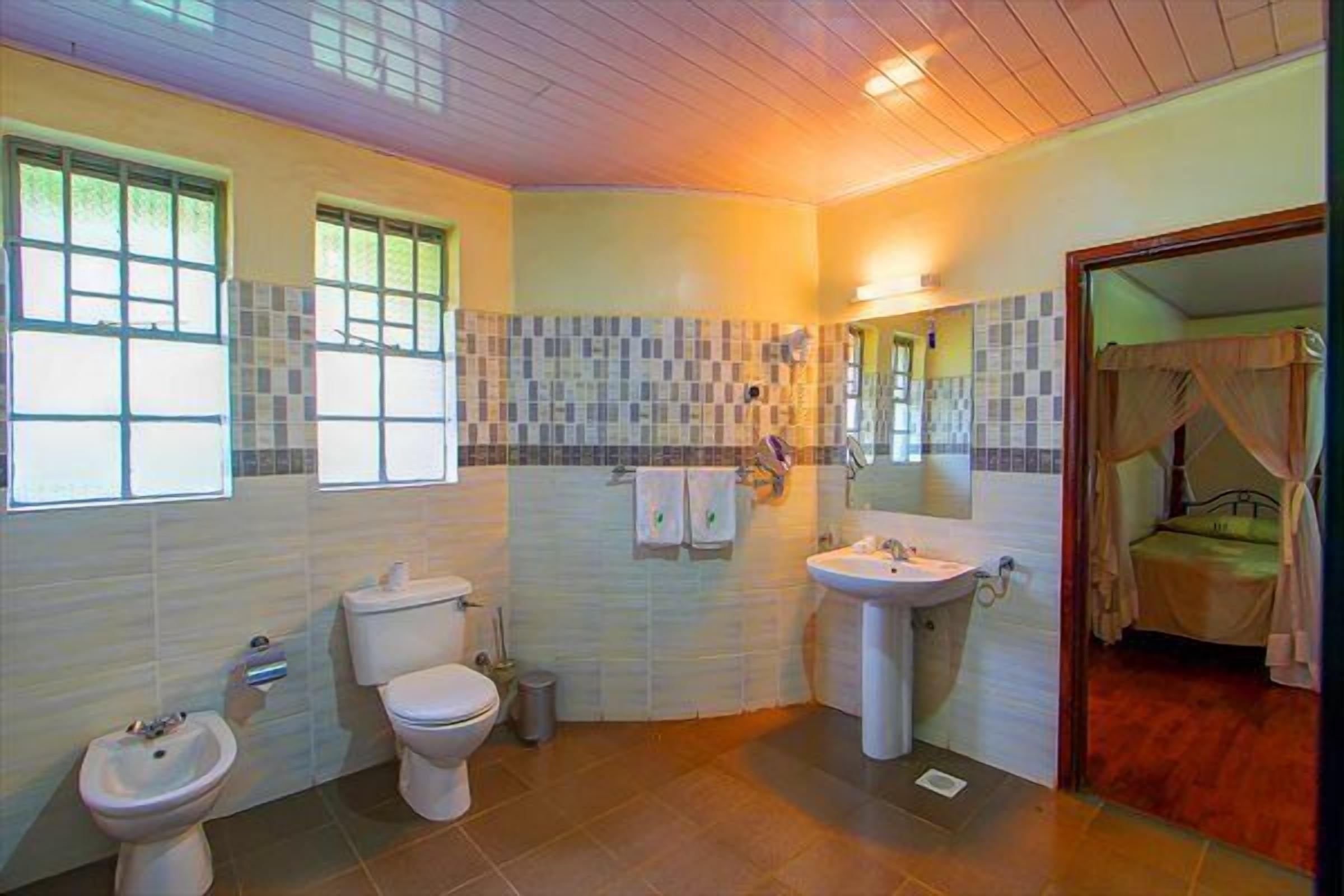 A bathroom with a toilet, bidet, sink, and a mirror.