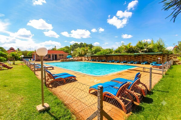 A swimming pool with lounge chairs and a fence. - Poa Place Resort & Hotel - Where Nature Meets Comfort Eldoret (Eldoret)