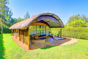 A thatched-roof structure with a stone patio, wooden furniture, and a view of the surrounding greenery. - Poa Place Resort & Hotel - Where Nature Meets Comfort Eldoret (Eldoret)