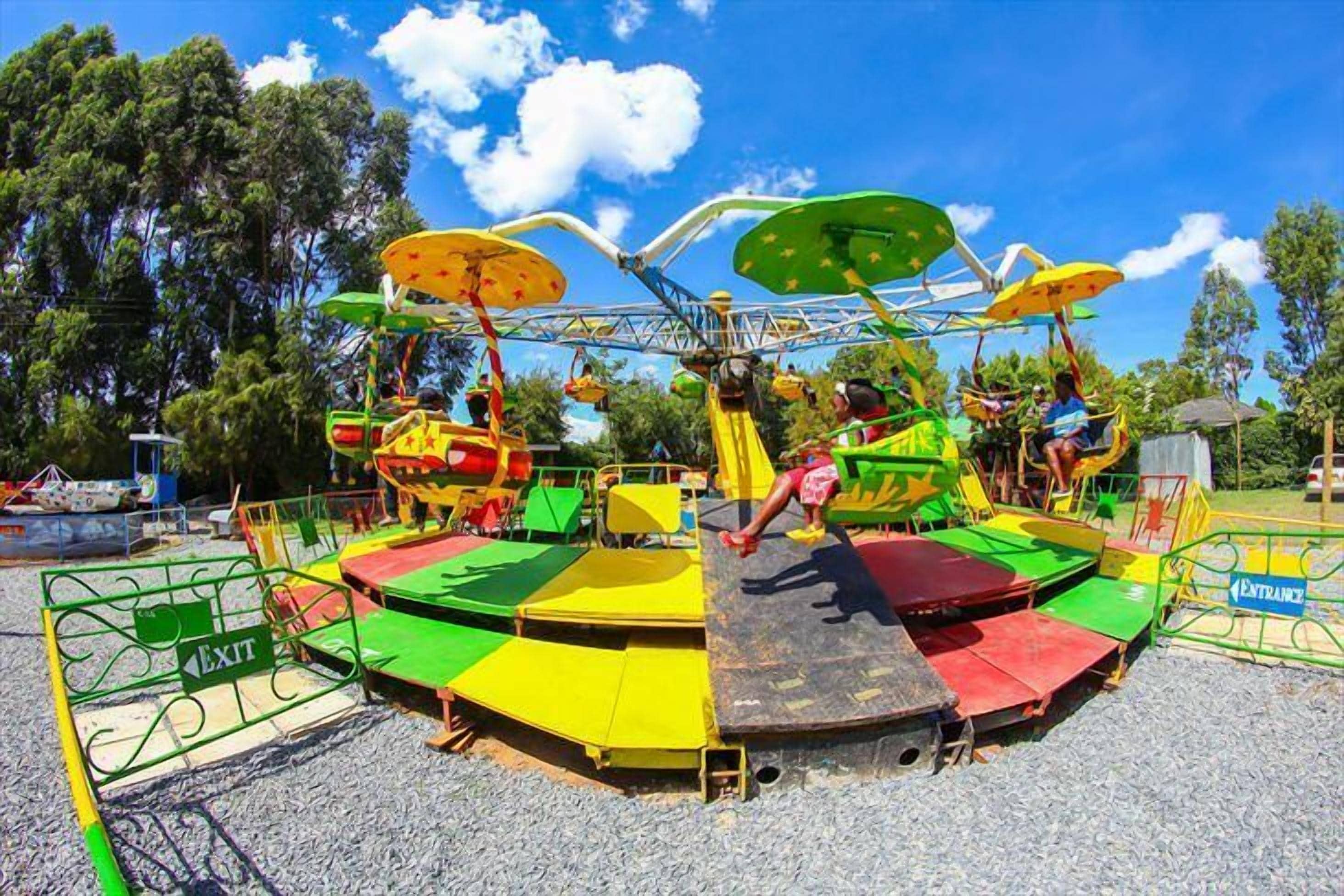 Une attraction colorée avec une plateforme circulaire et des sièges verts et jaunes.