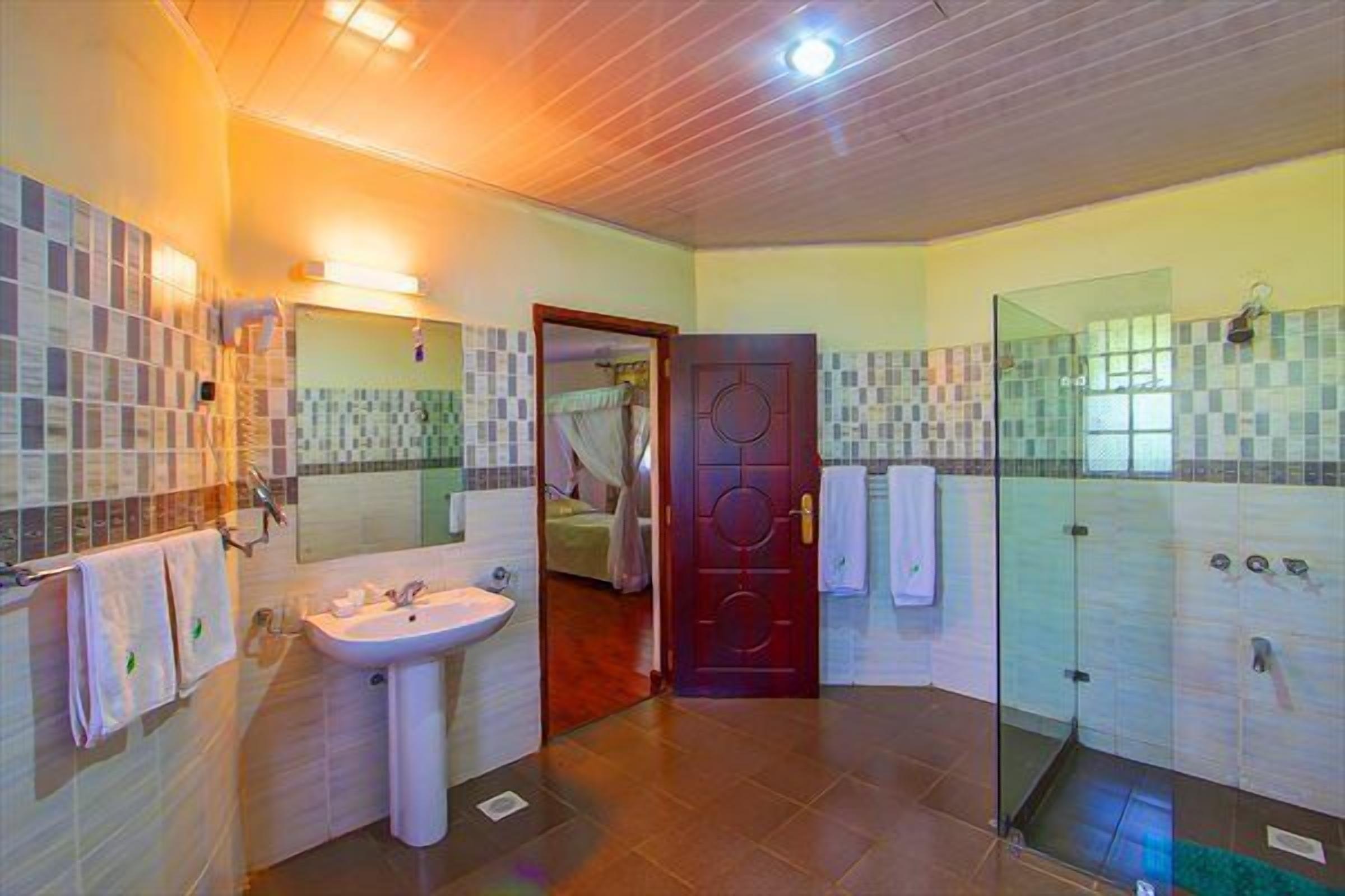 Ein Badezimmer mit Waschbecken, Spiegel, Dusche und einer Tür zu einem anderen Raum.