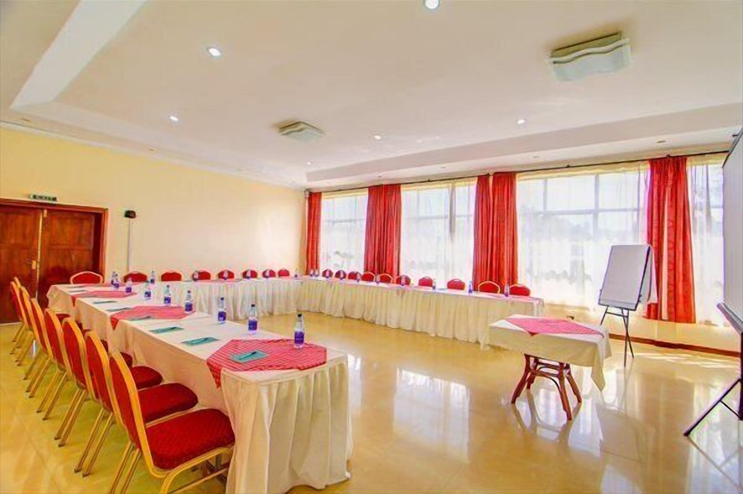 A conference room with a long table, red chairs, and a whiteboard.