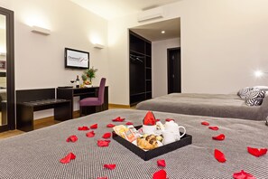 Habitació d'hotel amb un llit, una taula de nit i un armari. Hi ha un plat amb menjar i begudes damunt del llit.