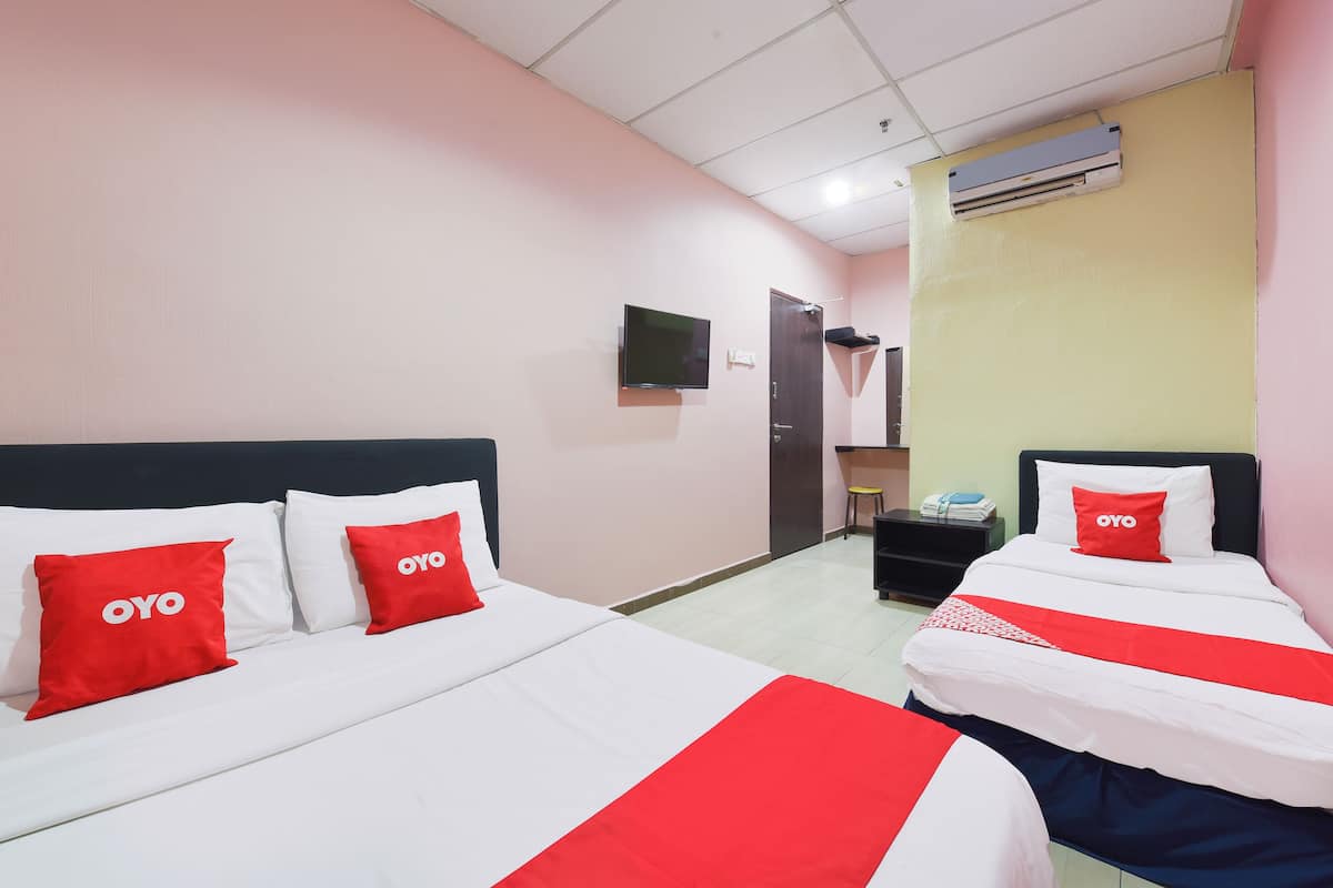 A hotel room with two beds, each with white and red bedding, and a television on the wall.