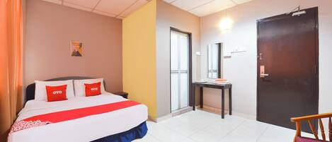Habitación de hotel con cama, escritorio, silla, puerta y ventana.