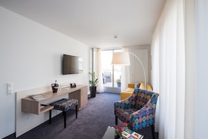 Una habitación de hotel moderna con escritorio, silla y sofá.