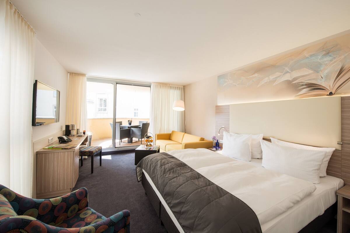 Una habitación de hotel con una cama grande, un escritorio, un sofá y una zona de comedor con vistas.
