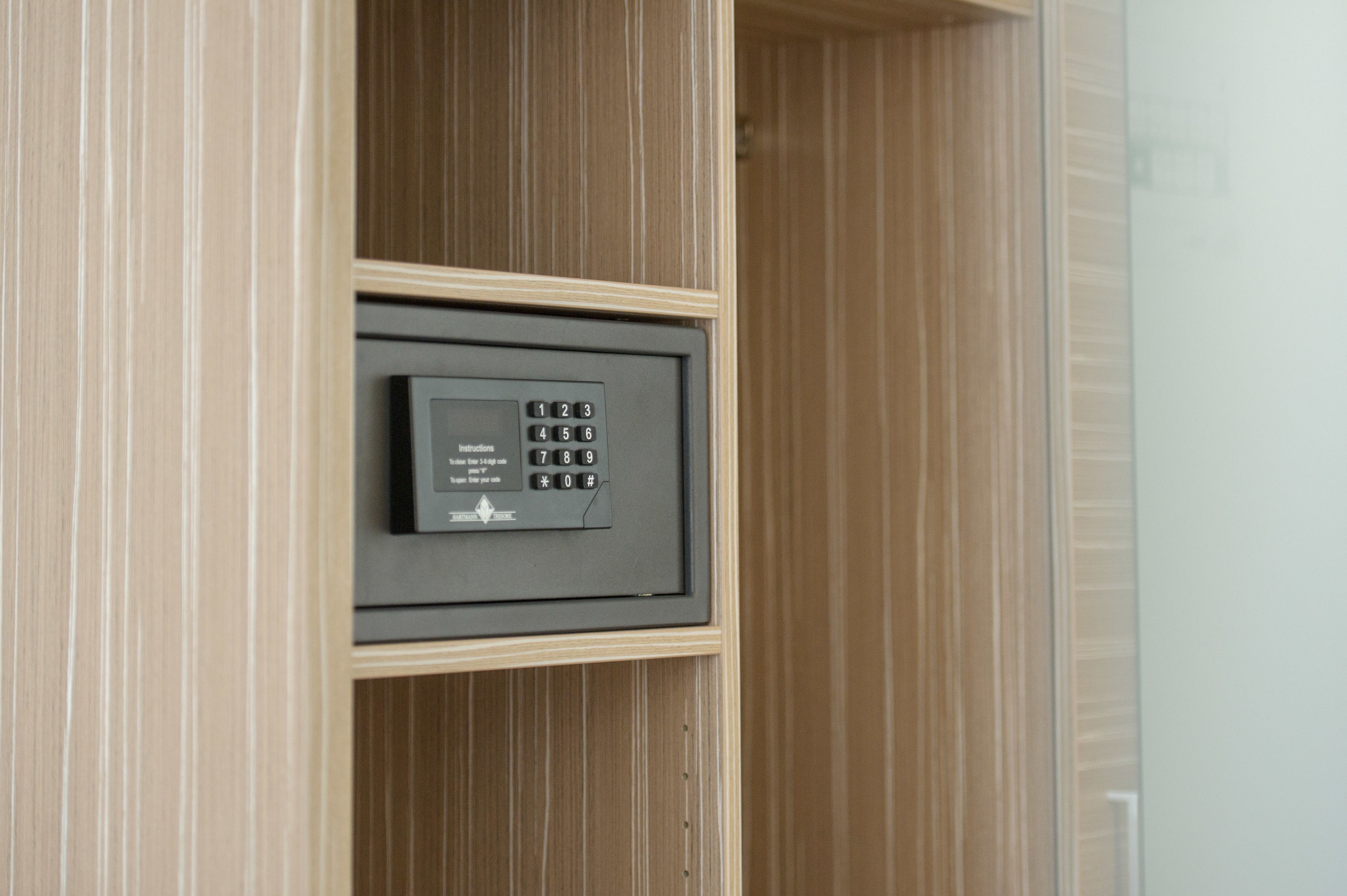 A secure safe with a keypad, located within a wooden cabinet.
