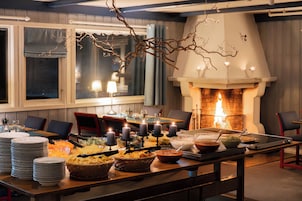 A dining area with a fireplace, tables set with plates, bowls, and candles.