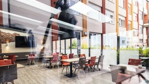 A modern restaurant with a long dining area, multiple tables, and chairs. - home Hotel (Wilhelmshaven)