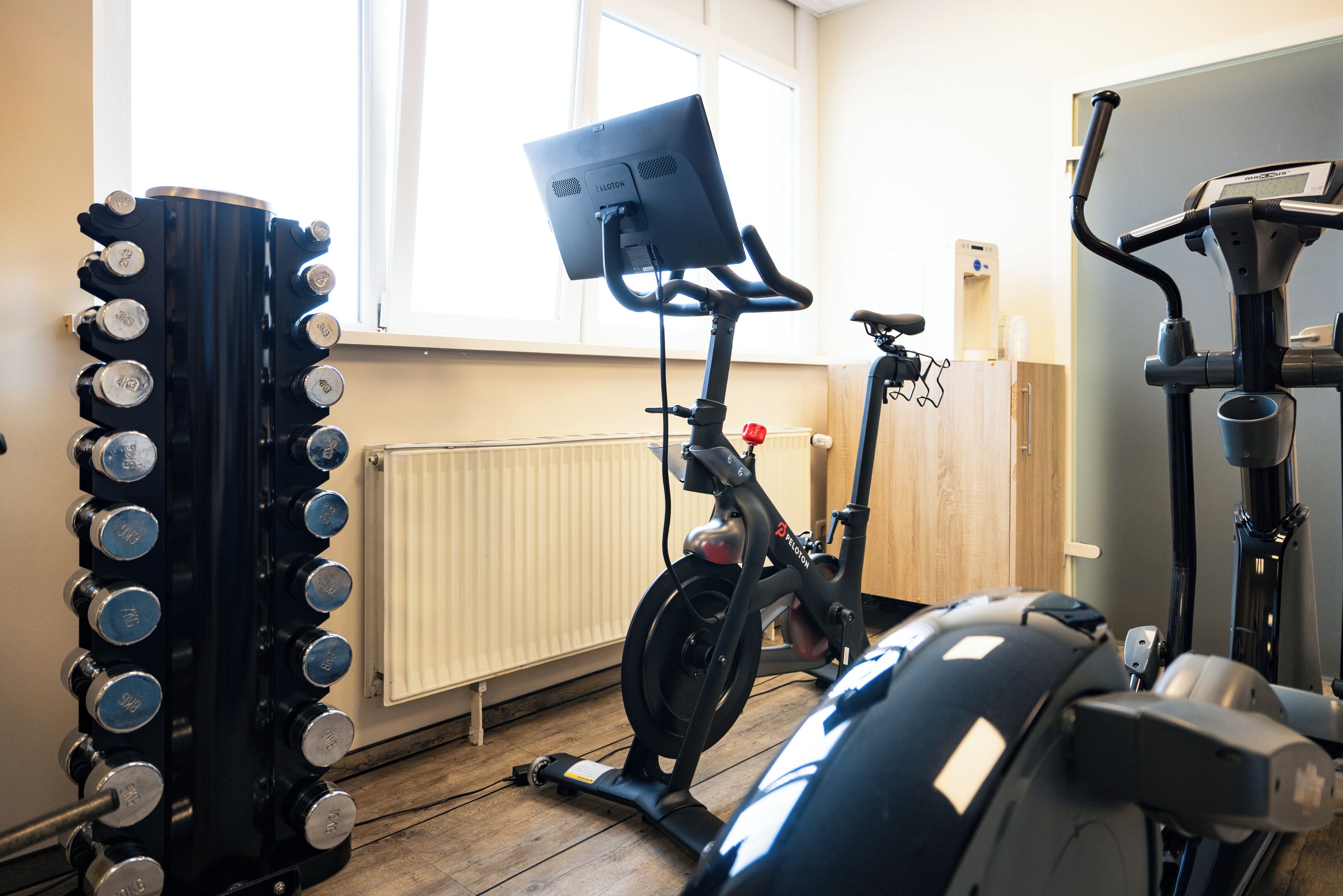 A home gym with a stationary bike, an elliptical trainer, and a weight bench.