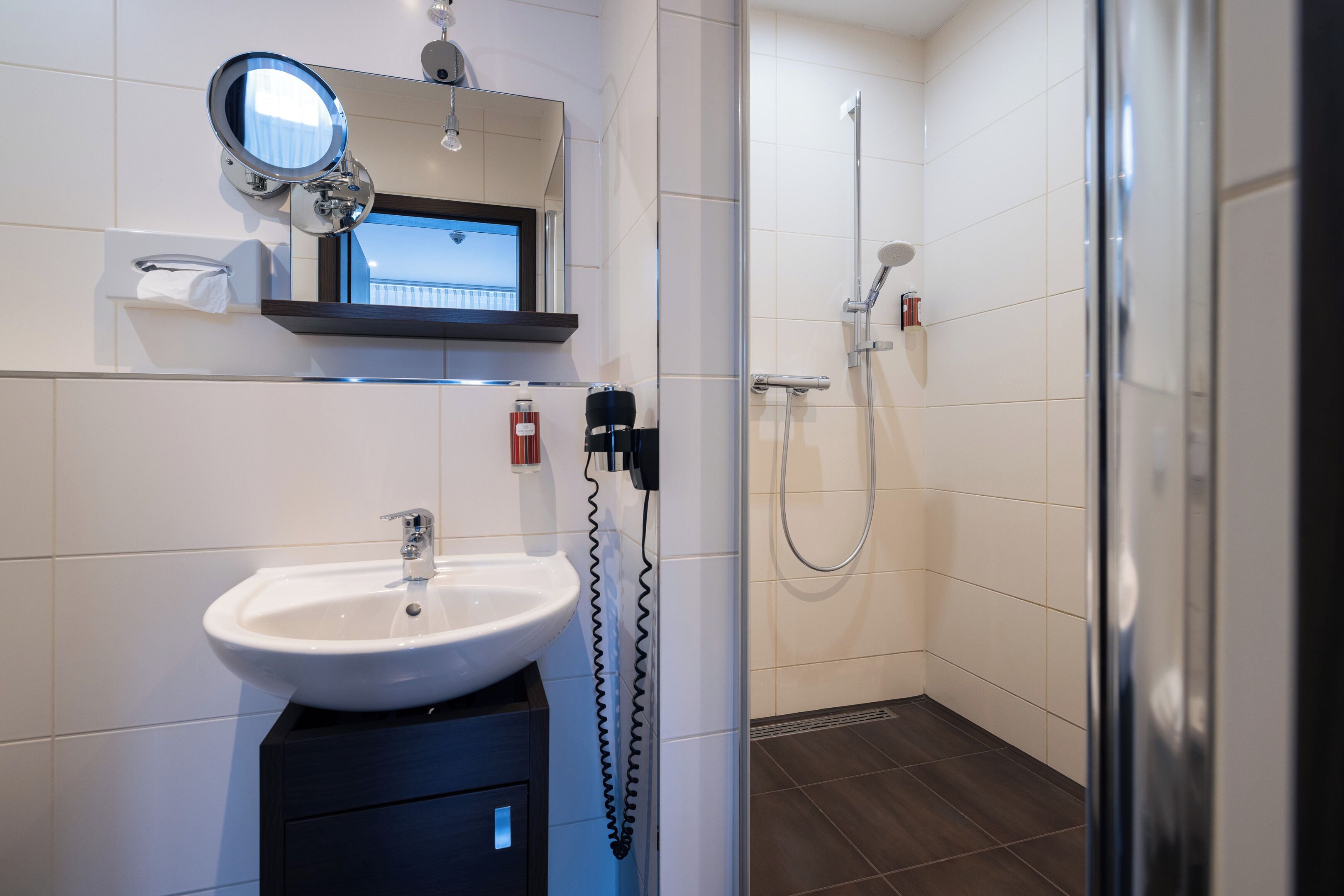 Ein modernes Badezimmer mit Waschbecken, Spiegel und Dusche.