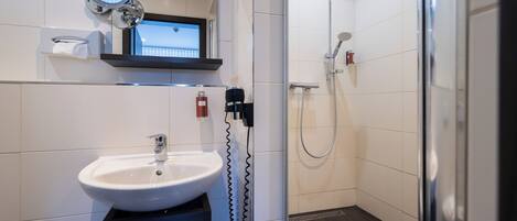 A modern bathroom with a sink, mirror, and shower.