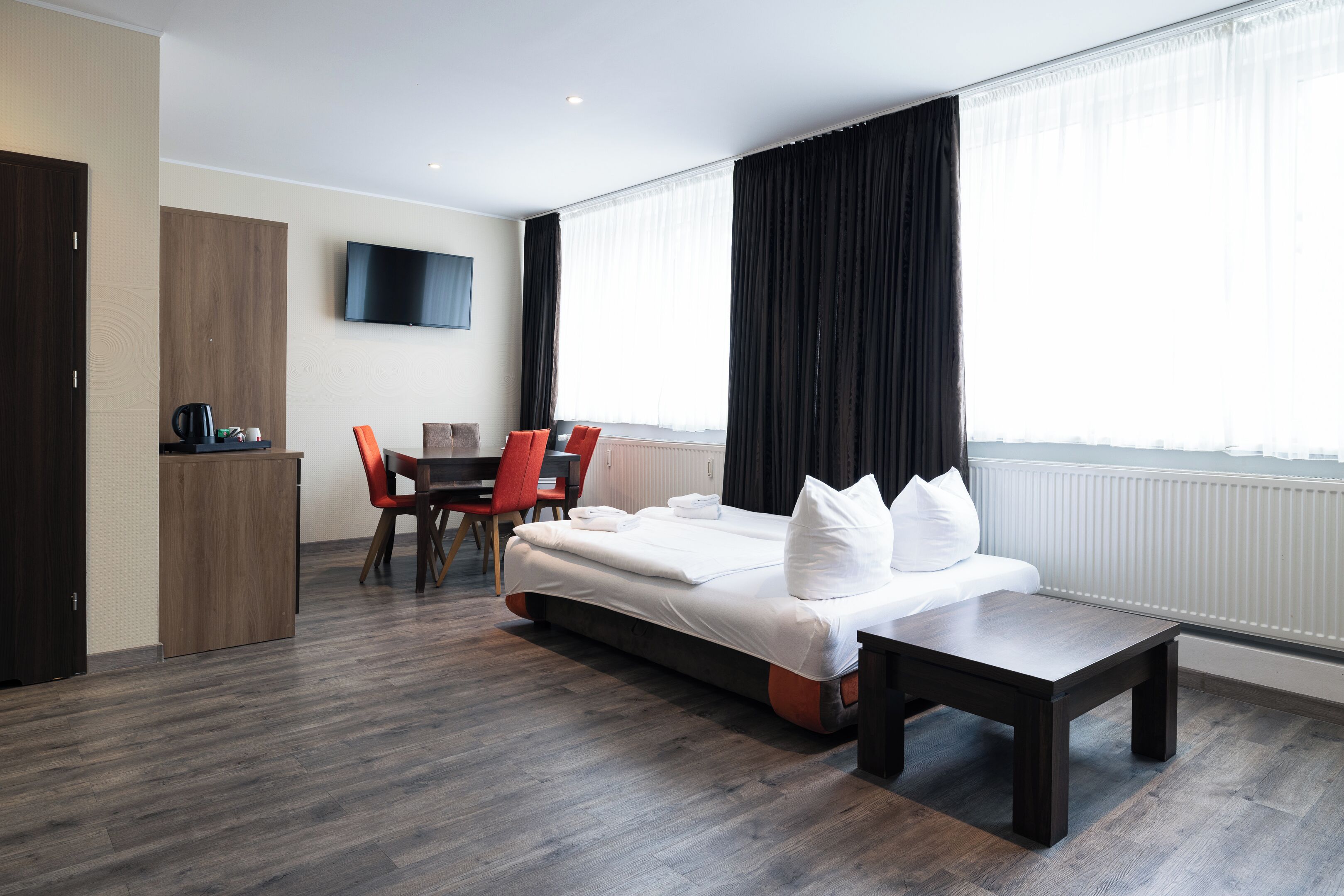 A modern hotel room with a large bed, a desk, and a TV.