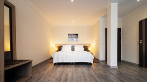 A modern hotel room with a large bed, wooden flooring, and a painting on the wall. - home Hotel (Wilhelmshaven)