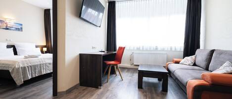 A modern hotel room with a bed, desk, and sofa.