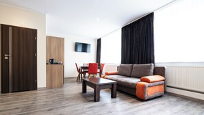 A modern living room with a sofa, coffee table, and dining area. - home Hotel (Wilhelmshaven)