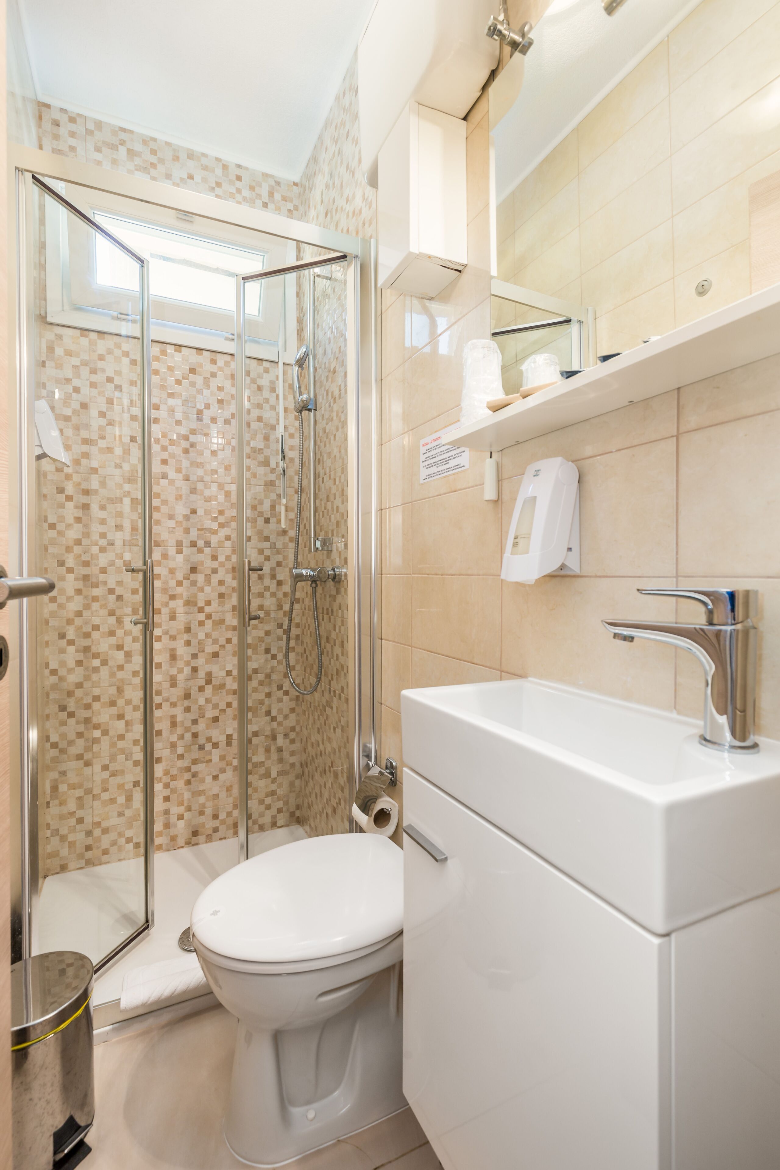 Un bagno con doccia vetrata, un water bianco e un lavabo con specchio sopra.