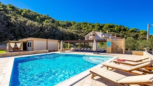 A swimming pool with lounge chairs and a building with a pergola in the background. - Lando Resort (Rab)