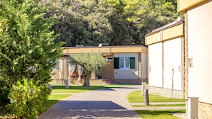 A pathway leading to a building with a stone facade and green shutters. - Lando Resort (Rab)