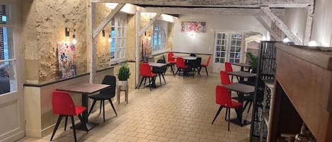 Un restaurante con paredes de ladrillo, sillas rojas y negras, y piso de baldosas.