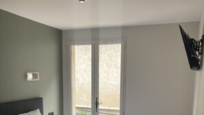 Un dormitorio con una cama grande, una mesita de noche, un control remoto y vistas al exterior a través de una puerta corrediza.