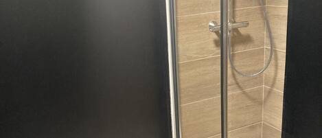 Un baño moderno con cabina de ducha de vidrio, suelo de madera y paredes oscuras.