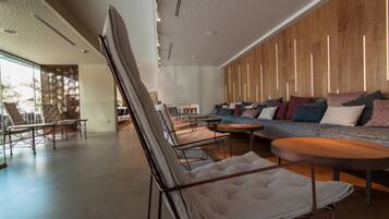 Een modern interieur met een bank, stoelen en een groot schilderij.