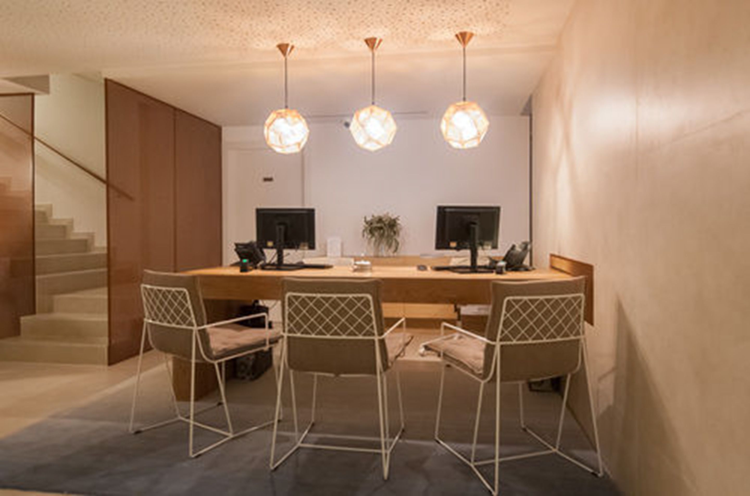 A modern kitchen with a central island, three pendant lights, and a staircase on the left.