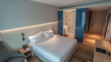 Una habitación de hotel moderna con una cama grande, mesitas de noche, un escritorio y un área de ducha.