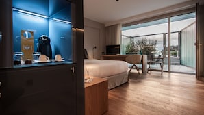 A modern hotel room with a large bed, a desk, a chair, a TV, and a balcony with a view. - Sorli Emocions (Vilassar de Dalt)